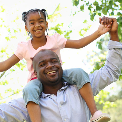 smiling black man with young black girl with braids on his shoulders