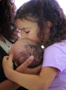 Sister kissing baby brother's head