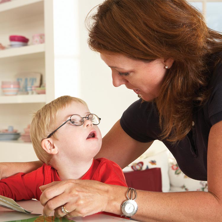 child with Downs Syndrome gazing at a woman with curly hair